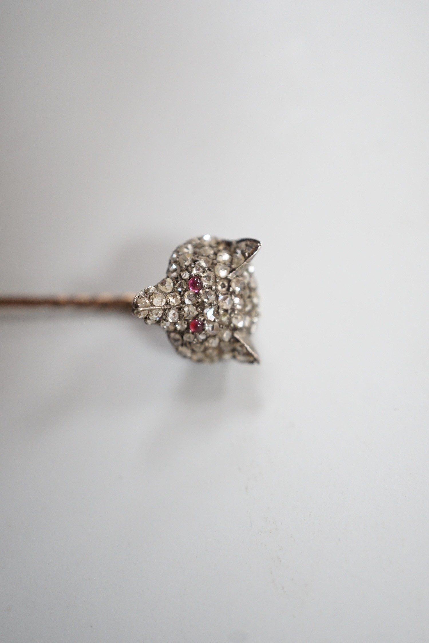 A late Victorian yellow and white metal, cabochon ruby? and rose cut diamond set fox head stick pin, 56mm, gross weight 4.7 grams (two stones missing).